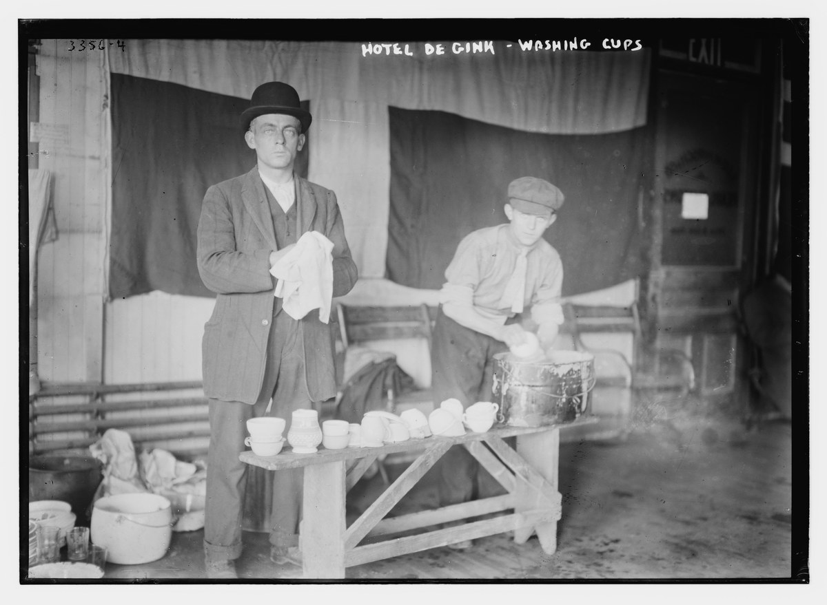 Two men washing cups at the Hotel de Gink lodging house