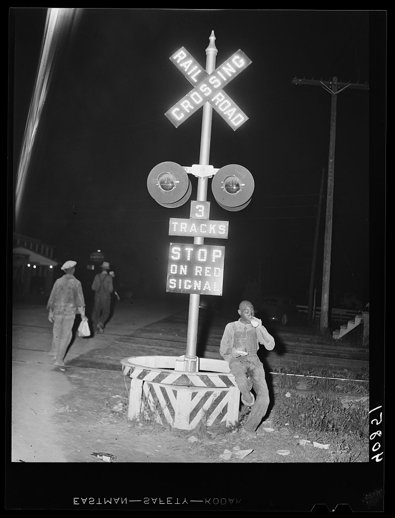 Migratory worker eating a nickel pie and milk at a railroad crossing, Camden, North Carolina