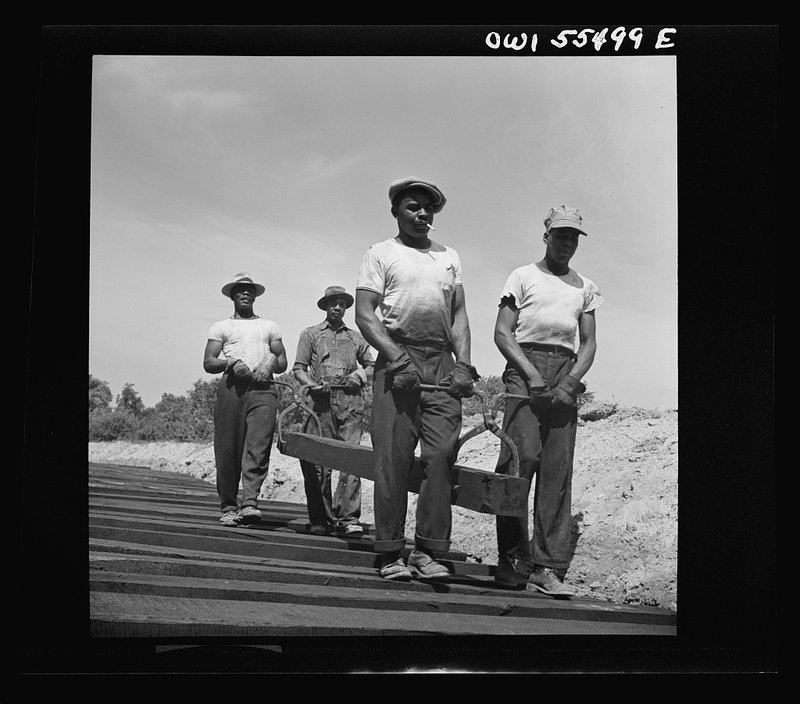 Black laborers carrying and laying railroad ties for a federal coal-storage spur